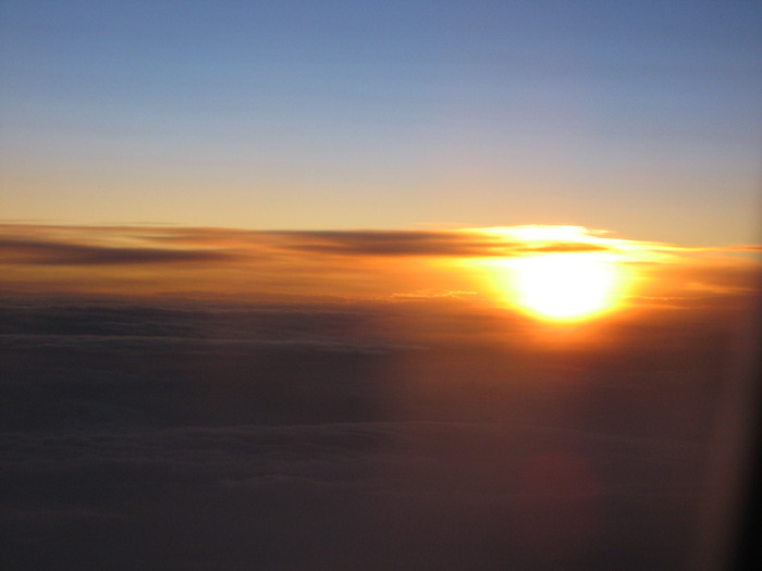 apus de soare vazut din avion; pe cer, se formeaza curcubeul penru cateva secunde
