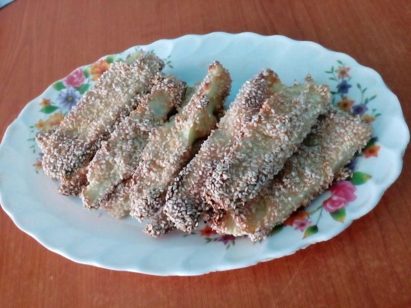 Sticksuri de dovlecel la cuptor; Ingrediente: 150g smântână, 1 dovlecel, 1 ou, 3-4 căței usturoi pisati, 60g brânză telemea, susan
