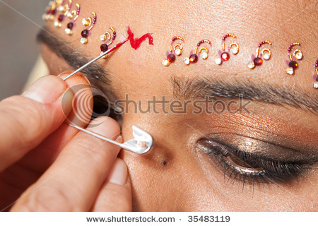 stock-photo-a-red-bindi-is-applied-to-a-hindu-brides-forehead-35483119