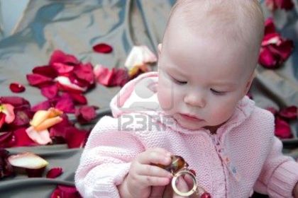781153-cute-baby-girl-sitting-and-looking-to-the-red-beads-in-her-hands-rose-s-petals-are-around-her