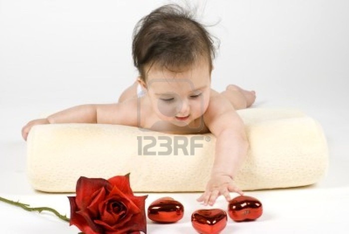 4103814-a-sweet-little-baby-girl-reaching-for-a-rose-and-some-heart-shaped-ornamets