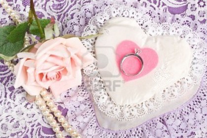 5365776-close-up-of-engagement-ring-on-pink-felt-heart-with-rose-and-pearls-in-background