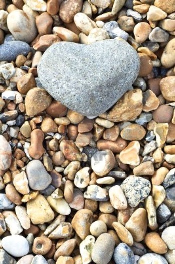 8698510-a-grey-heart-shaped-stone-in-upper-frame-resting-on-a-variety-of-smaller-stones-portrait-ver