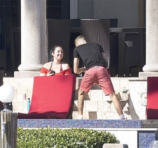 — Maniera în care mestecă respectivul dumicat devine din nou una lentă, sesizând brusca ei; schimbare de atitudine. Sprânceană dreaptă și-o înalță din nou și, realizând care era de fapt intenția mamei sale, imediat ce înghite, buzele în continuare lipite i se unduiesc pentru a forma un zâmbe
