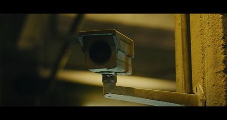 They gather around the steel gurney in the center of the room. The unconscious figure on it; looks half-dead—gaunt, gray-skinned, an oxygen mask taped over cracked lips. Beside the gurney: two buttons—one red, one green. On the far wall, a monitor flashes: “TREATMENT BEGINS IN 10:00.”
