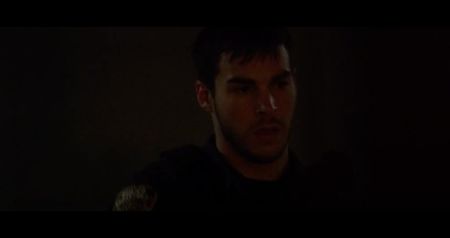 The gas clears slowly, leaving only the sour stench of burned metal and blood. The faint hum; of the ventilation system fades into silence. Four people rise coughing, their faces pale and streaked with soot. Holden doesn’t move. He’s slumped in his chair, his shirt burned open across the chest
